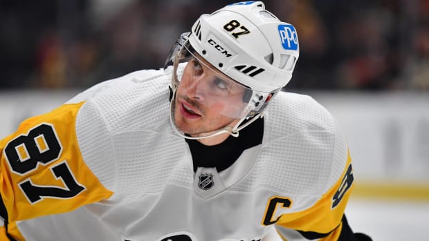Penguins forward Sidney Crosby looks up at an official before taking a faceoff during a game.